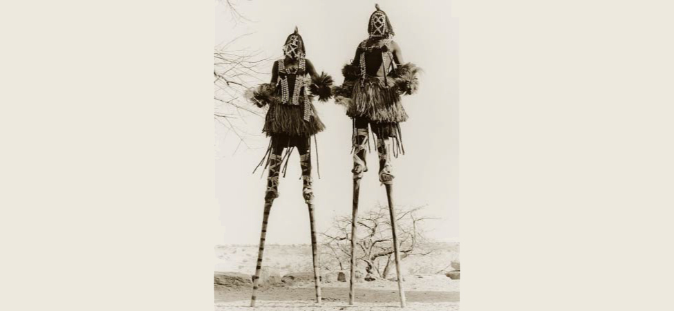 Picture shows a photograph of two stilt walkers in standing position.